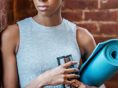A stack of yoga blocks and a rolled-up strap next to a water bottle.